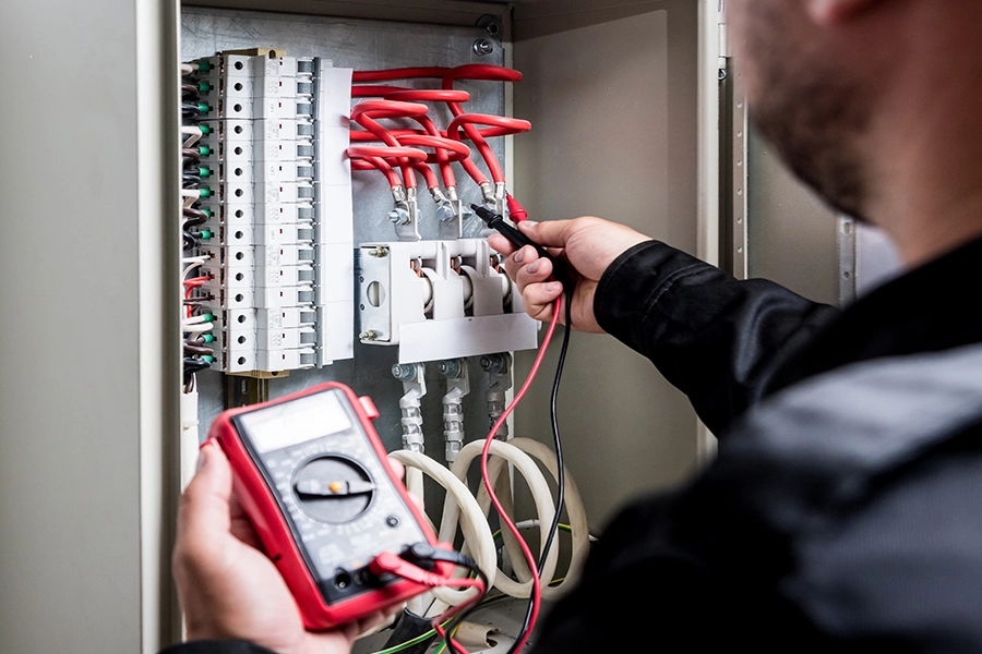 Electrician with multimeter tester analyzing the wiring in this Springfield IL home to determine if it needs a rewire.